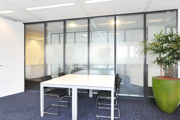Vergaderruimte aan de Laan van s-Gravenmade met glazen wanden, moderne inrichting en een grote kamerplant.